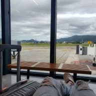 Júlio sitting waiting for his flight at Florianópolis airport, facing the plane parking area.